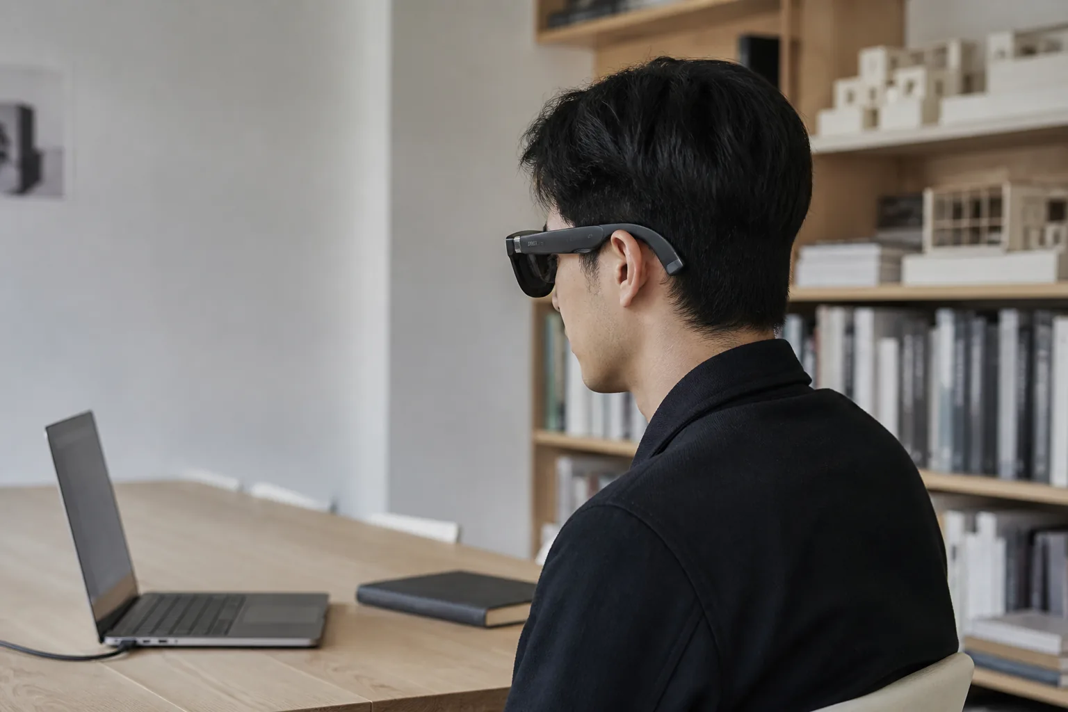 Reference-based editorial view of a person using XREAL One glasses at a quiet workspace